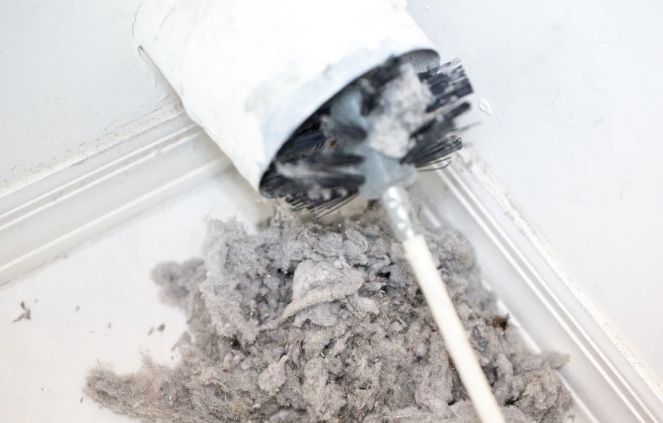 lint being removed with a brush from a dryer vent